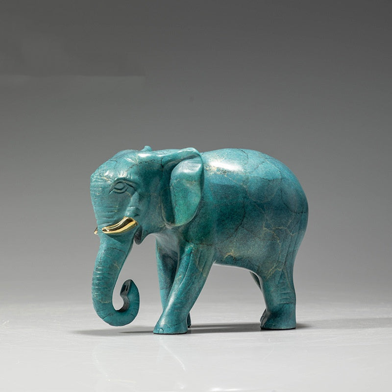 Angled front view of brass elephant statue with gold tusks