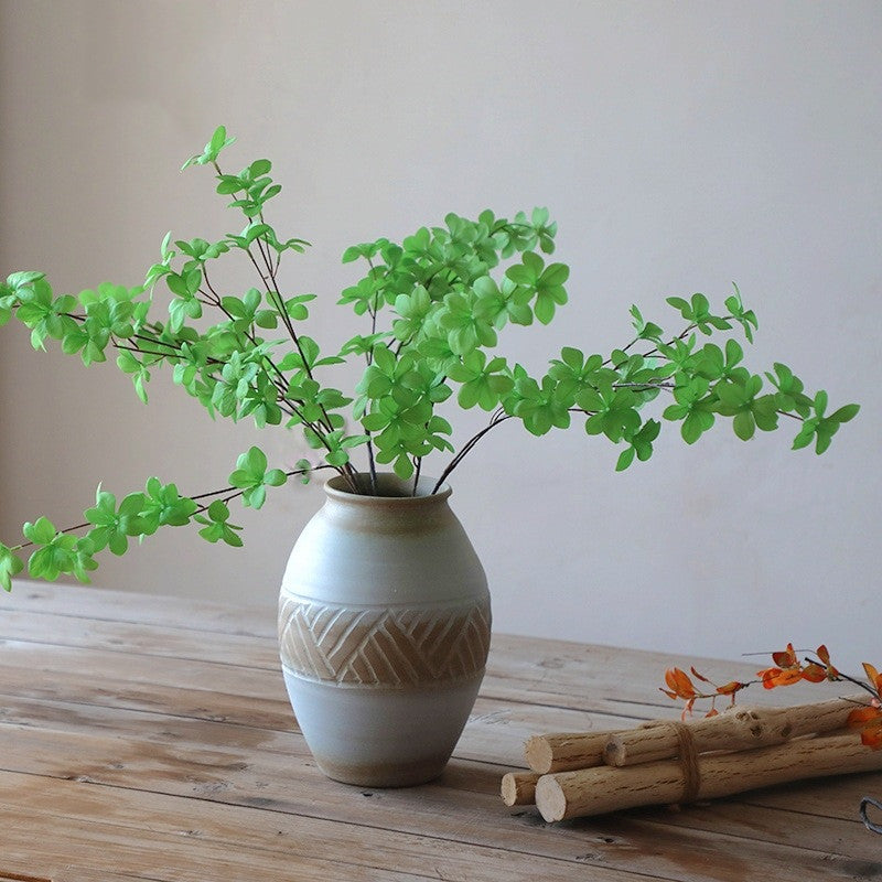 White and tan ceramic vase with green foliage