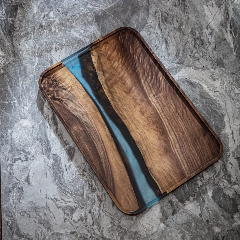 Top down view of rectangular walnut tray with blue epoxy river insert on marble surface