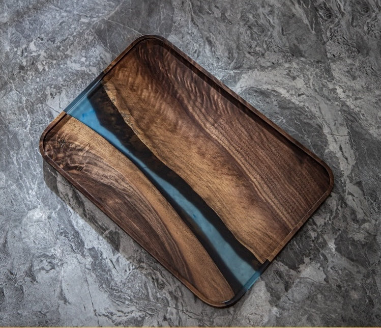 Angled view of handcrafted walnut tray showing wood grain and translucent blue epoxy resin