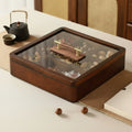 Closed wooden serving box with brass handle details on table