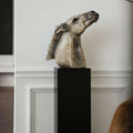 Weathered ceramic horse head sculpture side profile on black pedestal