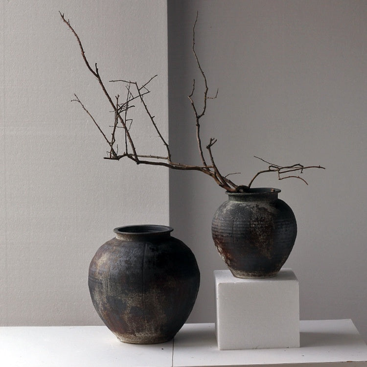 Weathered dark ceramic vase with dry branches