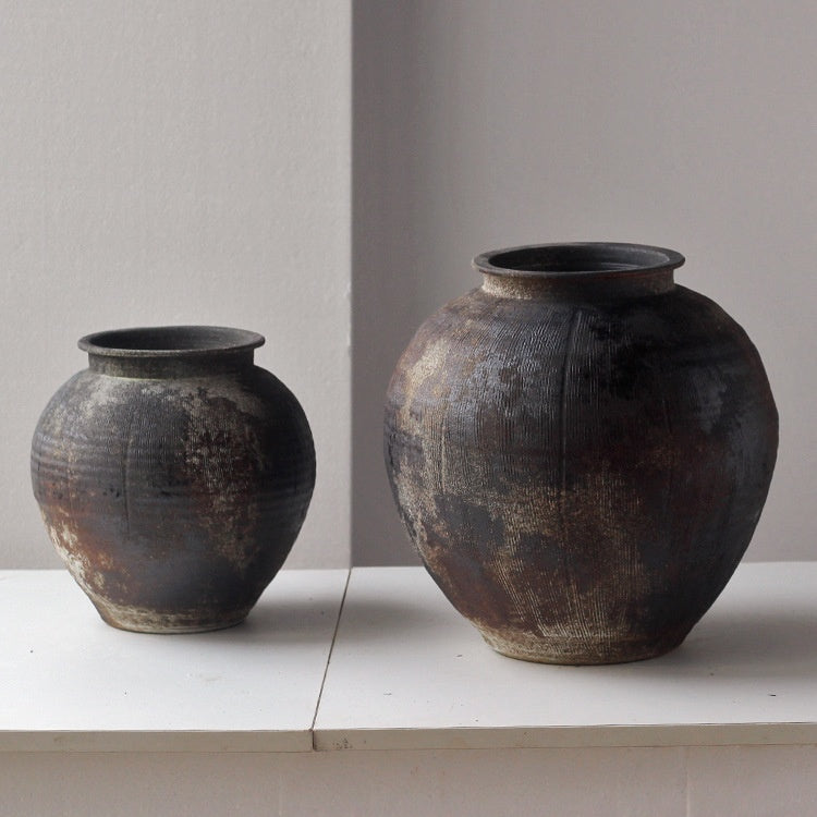 Two distressed black ceramic jars side by side
