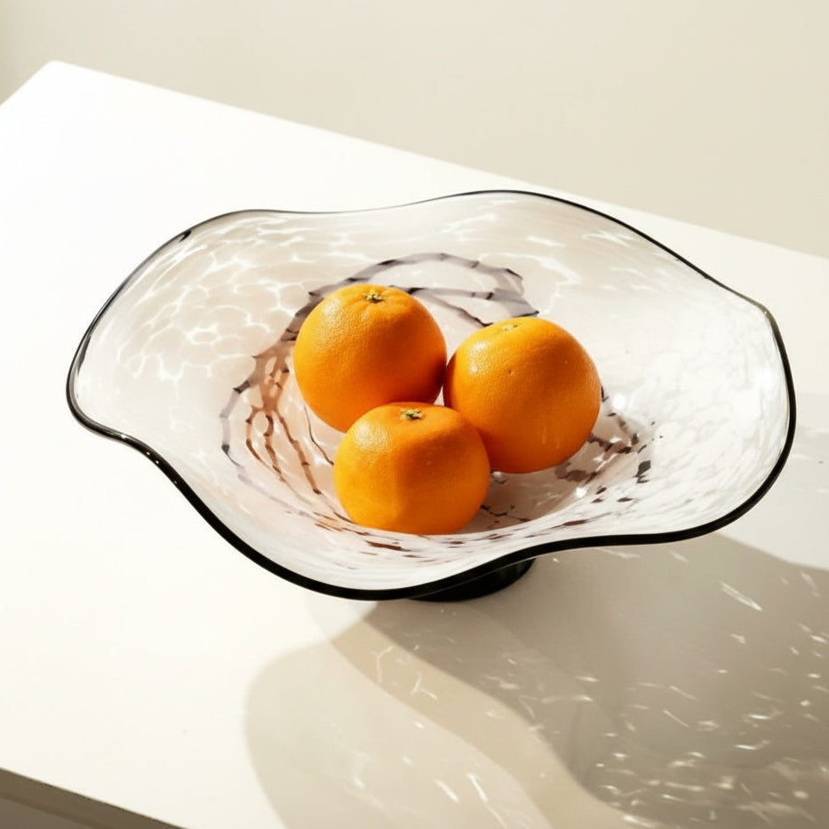 White and black marbled glass fruit bowl holding oranges