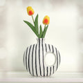 Front view of white and black striped ceramic donut vase with tulips