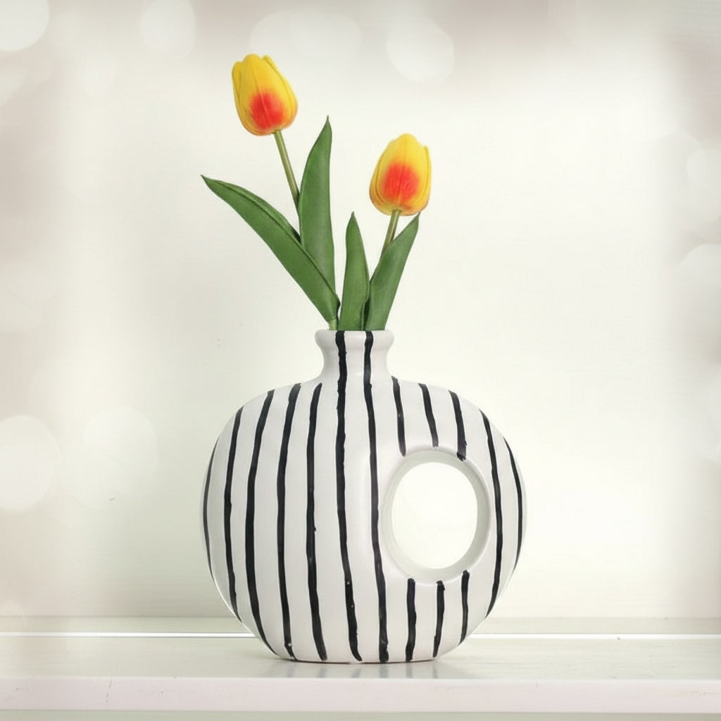 Front view of white and black striped ceramic donut vase with tulips
