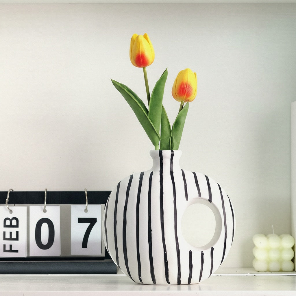 Striped ceramic circular vase on shelf with calendar and candle