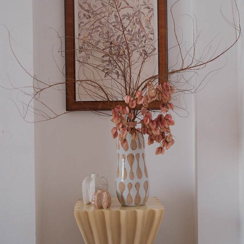 Ceramic vase with dried flowers on pedestal