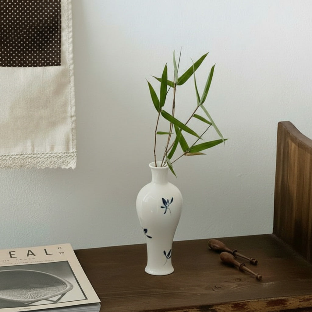 White ceramic botanical vase with green bamboo leaves
