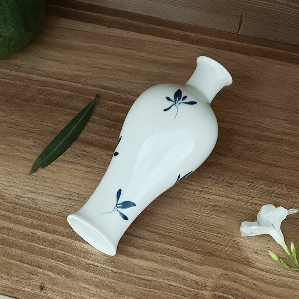 Angled view of white ceramic botanical vase laying down