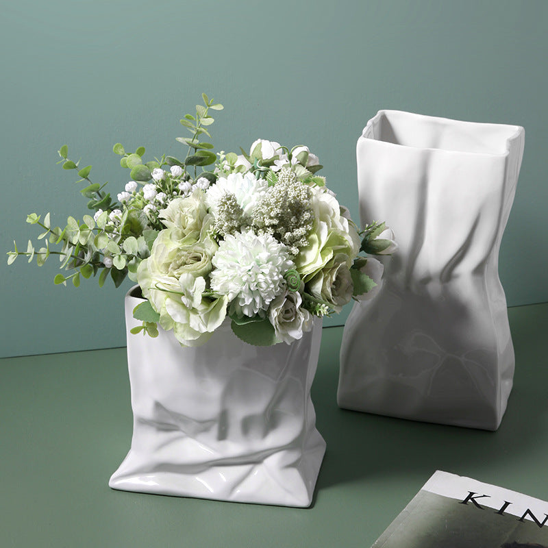 Pair of white ceramic crinkled paper bag vases with flowers