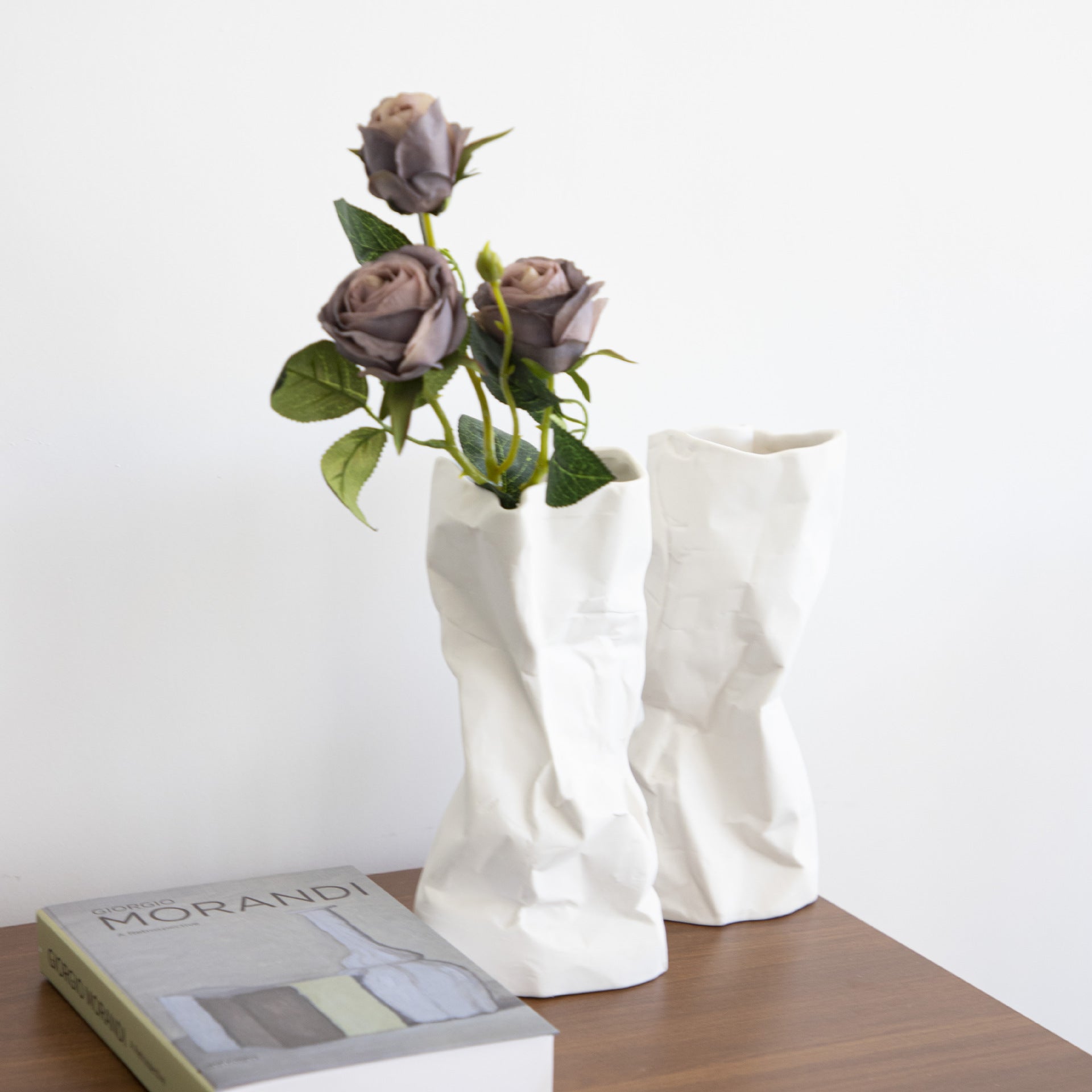 Stylized shot of white ceramic paper bag vase with flowers