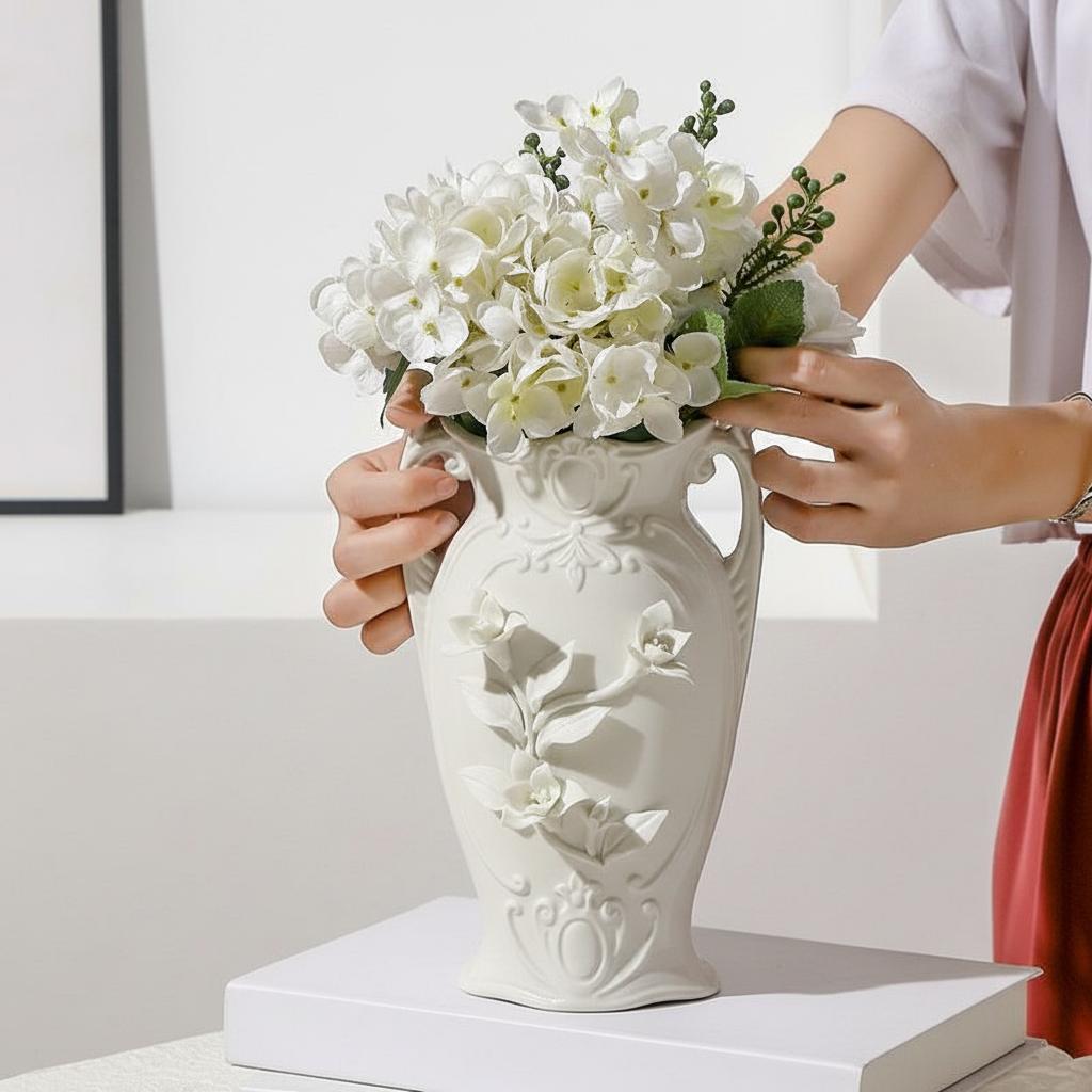 Hands arranging white flowers in embossed ceramic vase