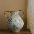 White ceramic vase with blue floral pattern and green double handles