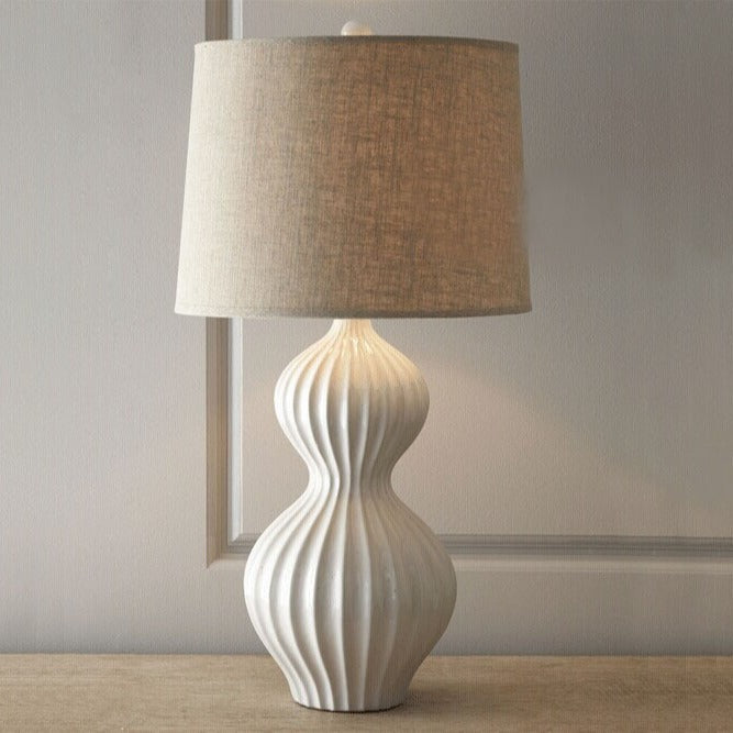 Lit white ceramic table lamp with linen shade