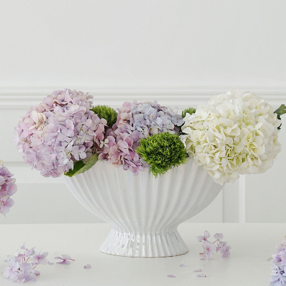 White ceramic pedestal bowl used as a floral vase with hydrangeas