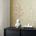 White ceramic gourd and gold branch sculpture on a console table