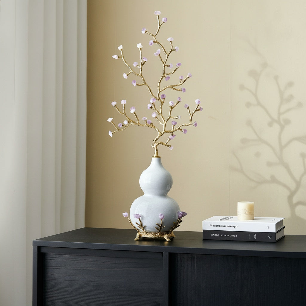 White ceramic gourd and gold branch sculpture on a console table