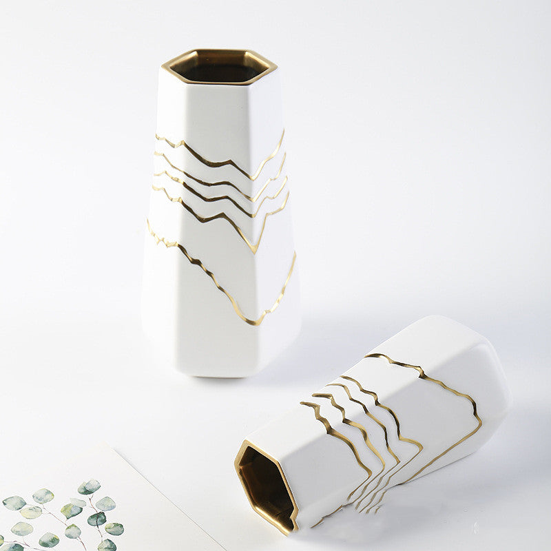 Set of two white and gold ceramic vases arranged artistically