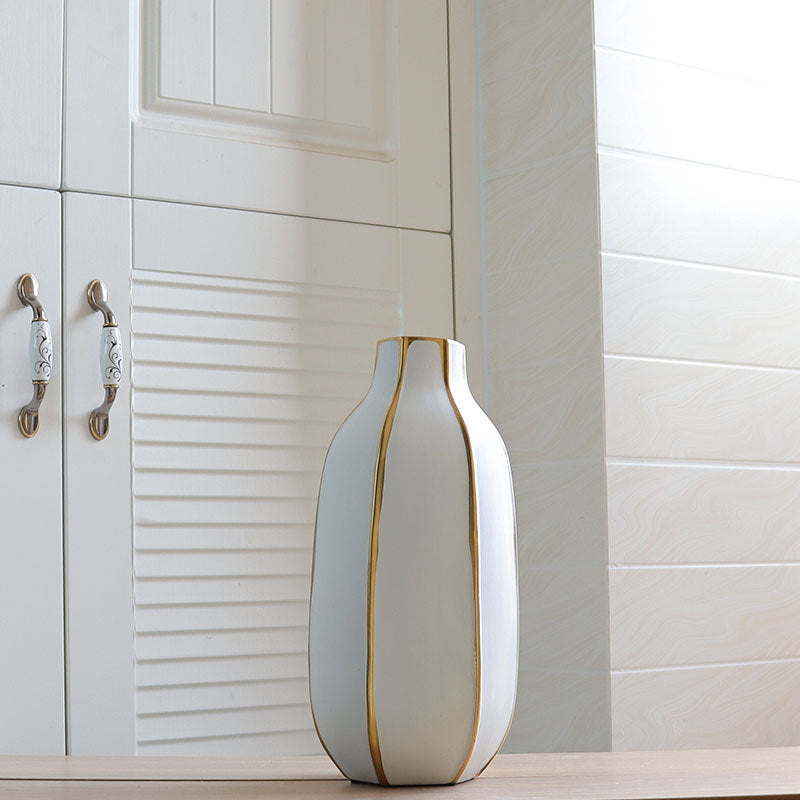 Close up of tall white vase with gold vertical stripes