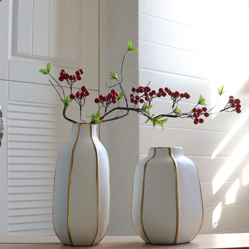 Two white and gold vases styled with red berries