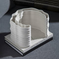 White Ceramic Ribbed Curved Sculpture resting on a book