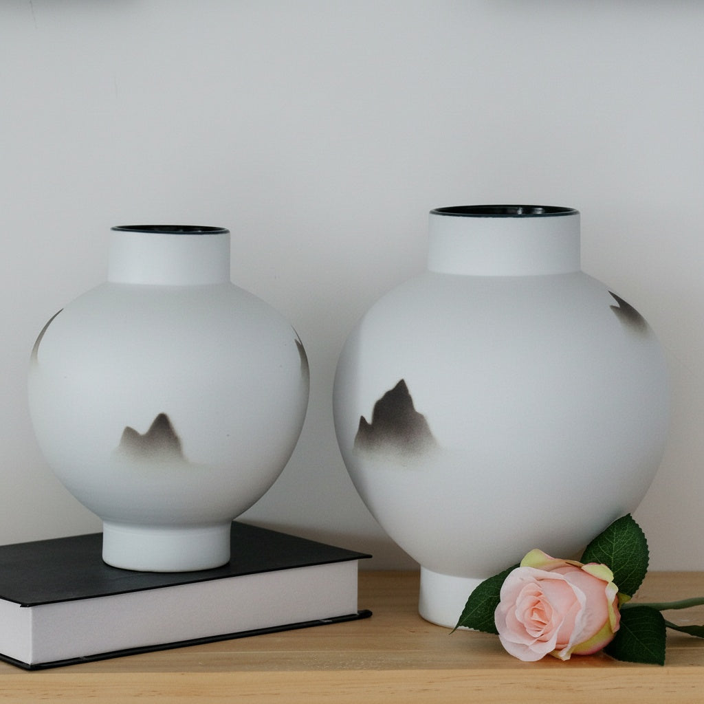 Two white ceramic spherical vases on a shelf