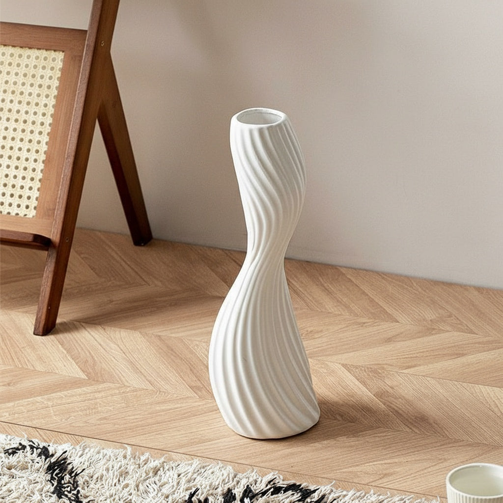 White ceramic twisted spiral vase standing on wooden floor
