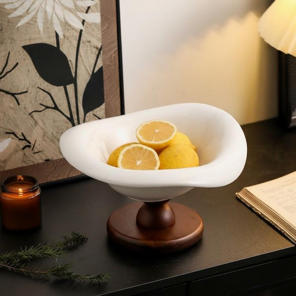 White ceramic wavy fruit bowl on dark wood pedestal base with lemons
