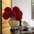 White fluted swirl handled urn vase with red hydrangeas on console