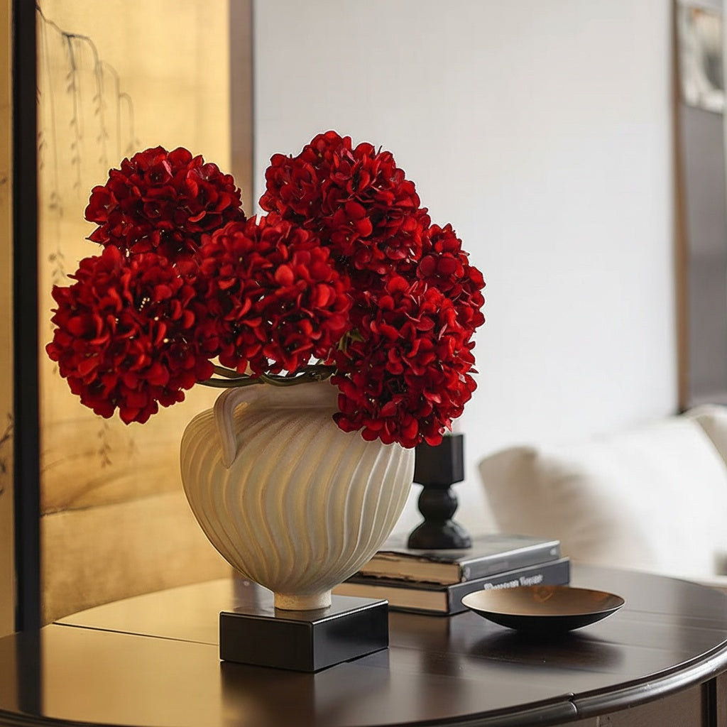 White fluted swirl handled urn vase with red hydrangeas on console
