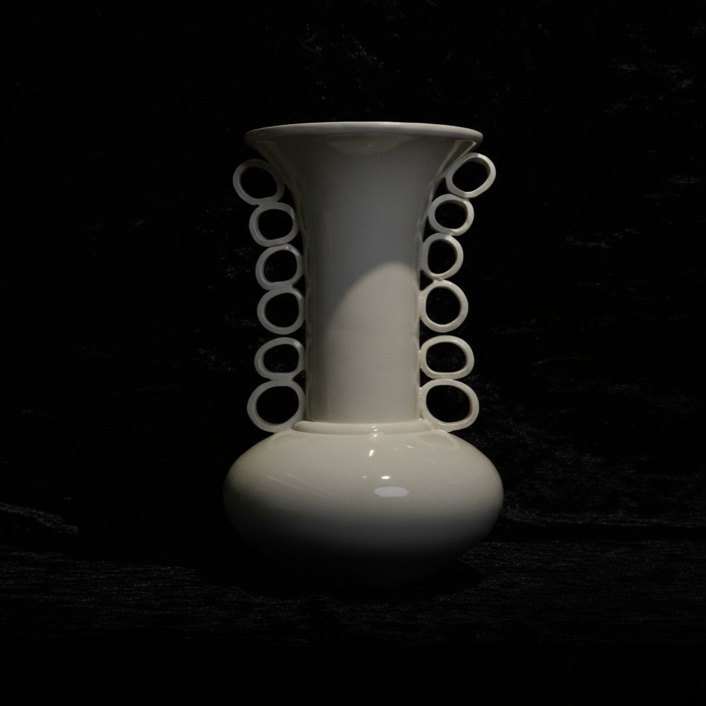 Front view of white ceramic vase with ring handles on black background