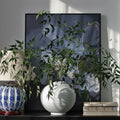 White Glazed Ceramic Spherical Vase styled with green branches on a console