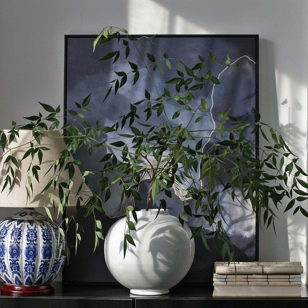 White Glazed Ceramic Spherical Vase styled with green branches on a console