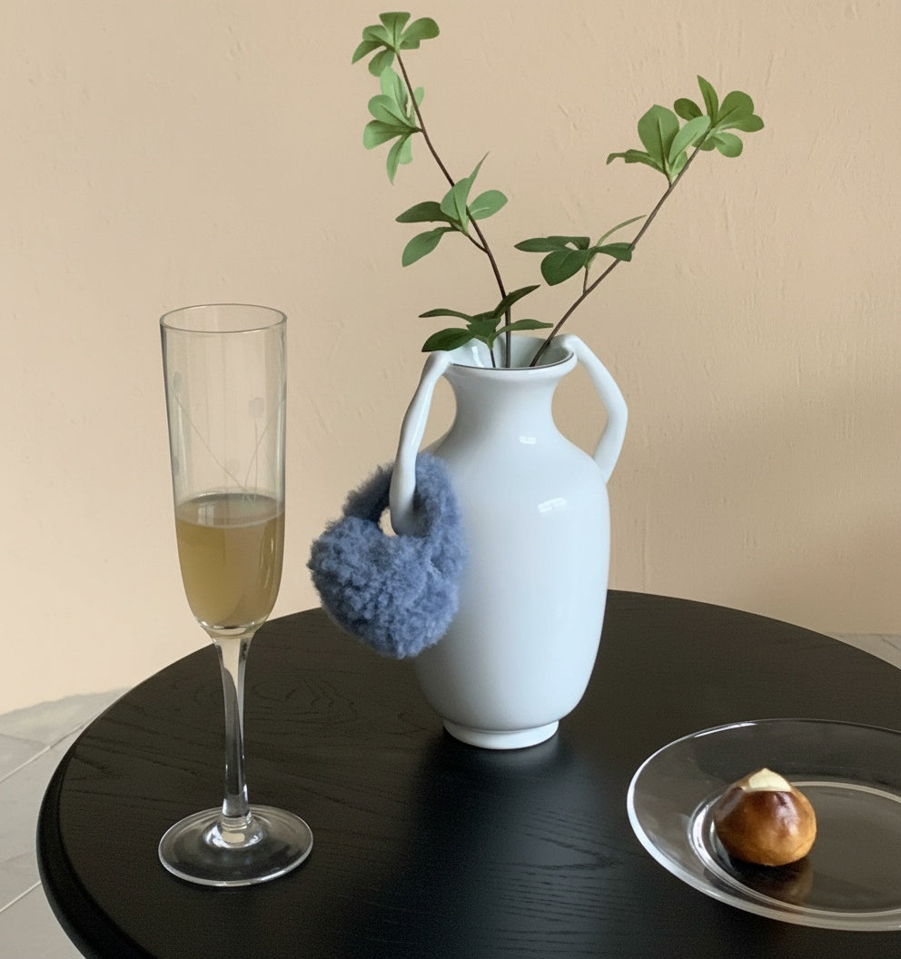 White ceramic twin handle vase styled on a black table