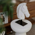 Front view of white horse head sculpture with gold veining on black stand