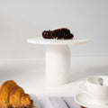 White marble pedestal stand displaying decorative pinecones