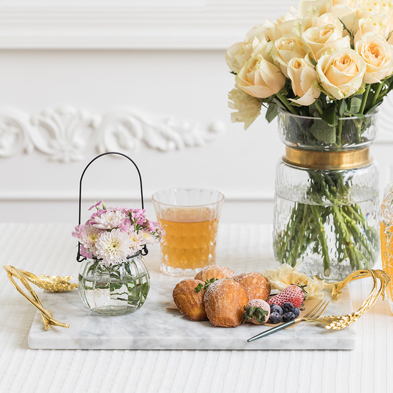 Elegant white marble serving tray with gold wheat handles displaying pastries and flowers