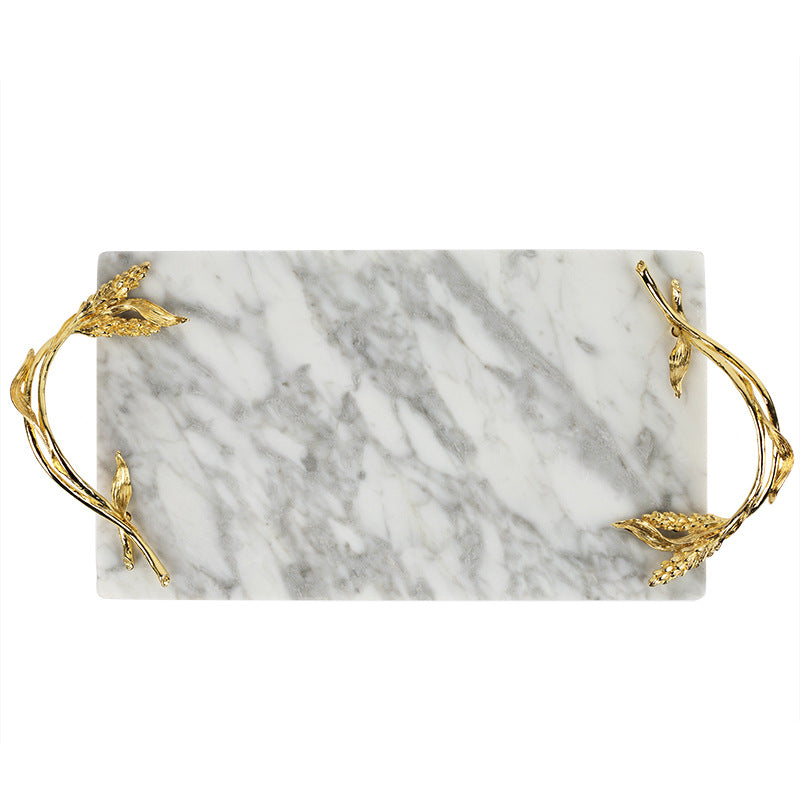 Top down view of rectangular white marble tray featuring sculptural gold wheat stalk handles