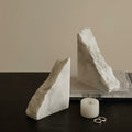 White marble triangular bookends displayed on a dark wooden table