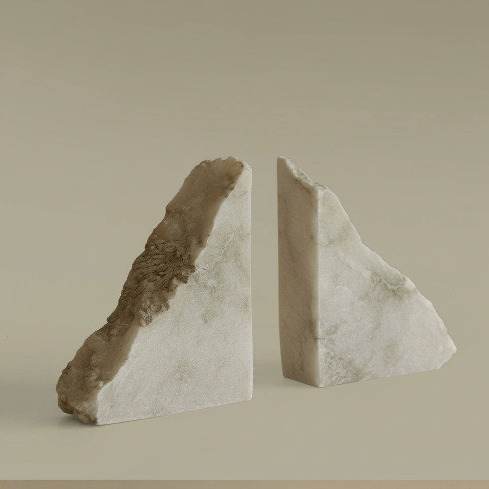 Close up of white marble triangular bookends showing the artisanal raw edge