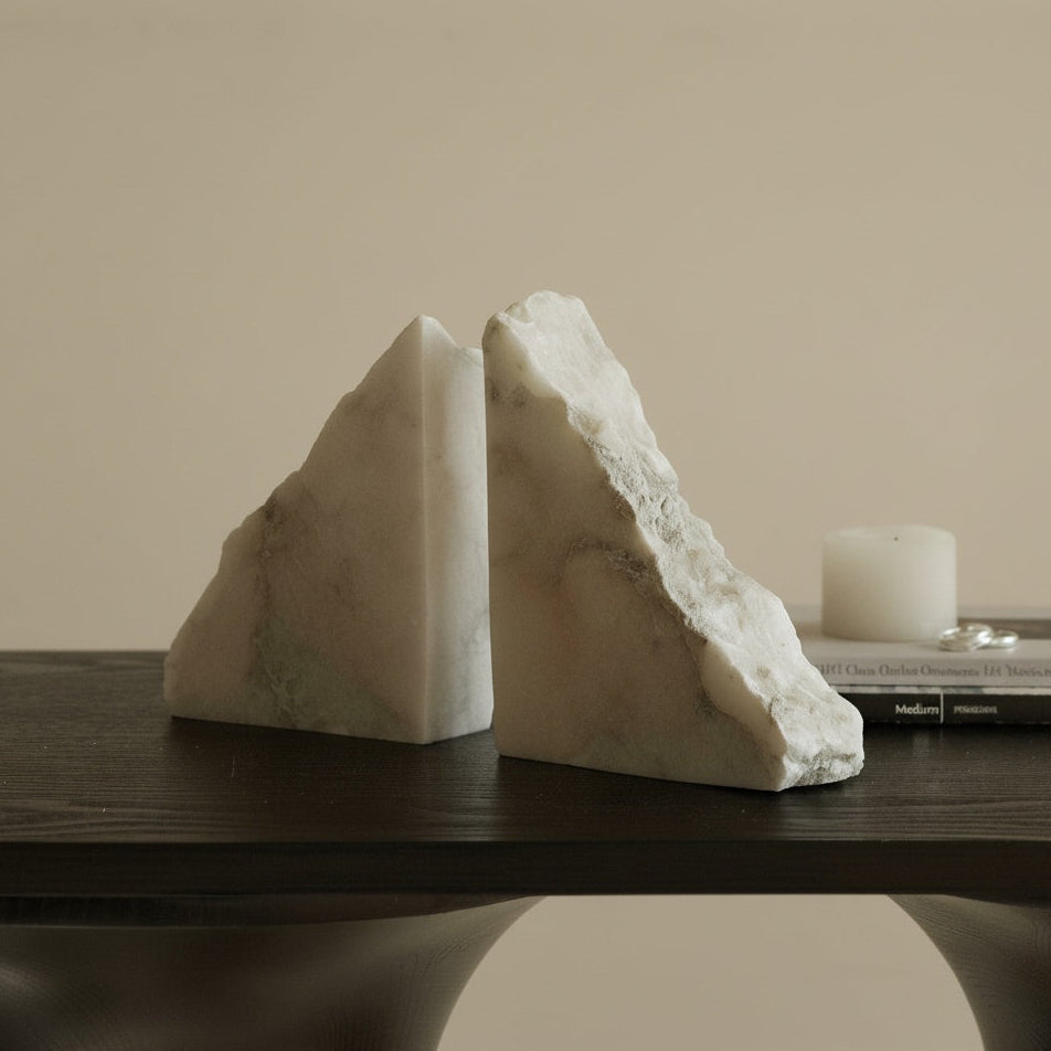 Angled view of white marble triangular bookends on a desk surface