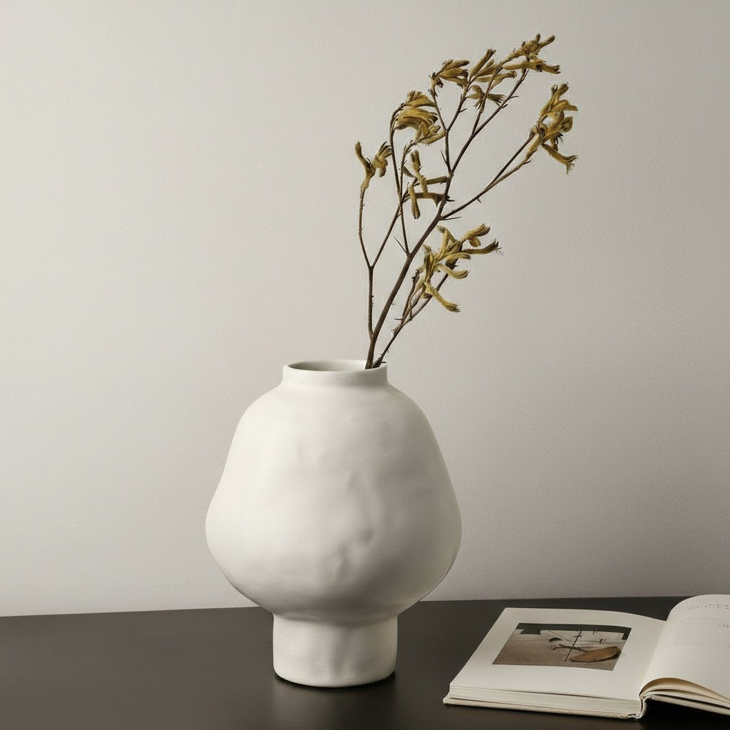 White matte ceramic bulbous vase with dried flowers on table