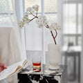White onyx vase with flowering branch on black marble table