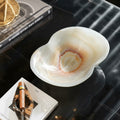 White onyx bowl on dark marble table with decor