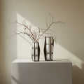 White opal glass vase with blackened metal cage frame holding branches