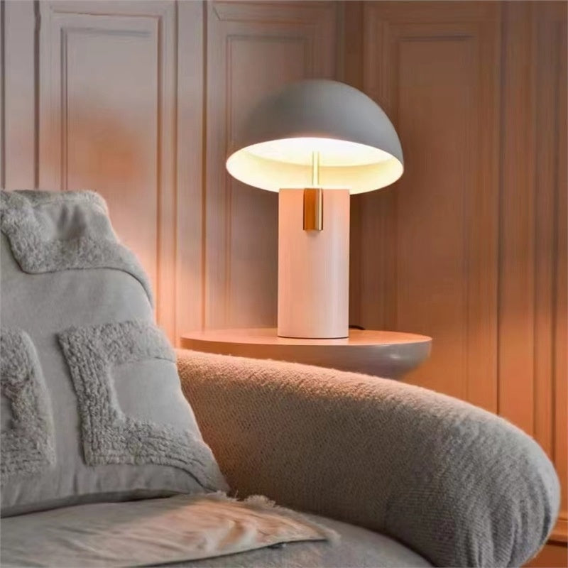 Illuminated white mushroom lamp with brass accent on bedside table