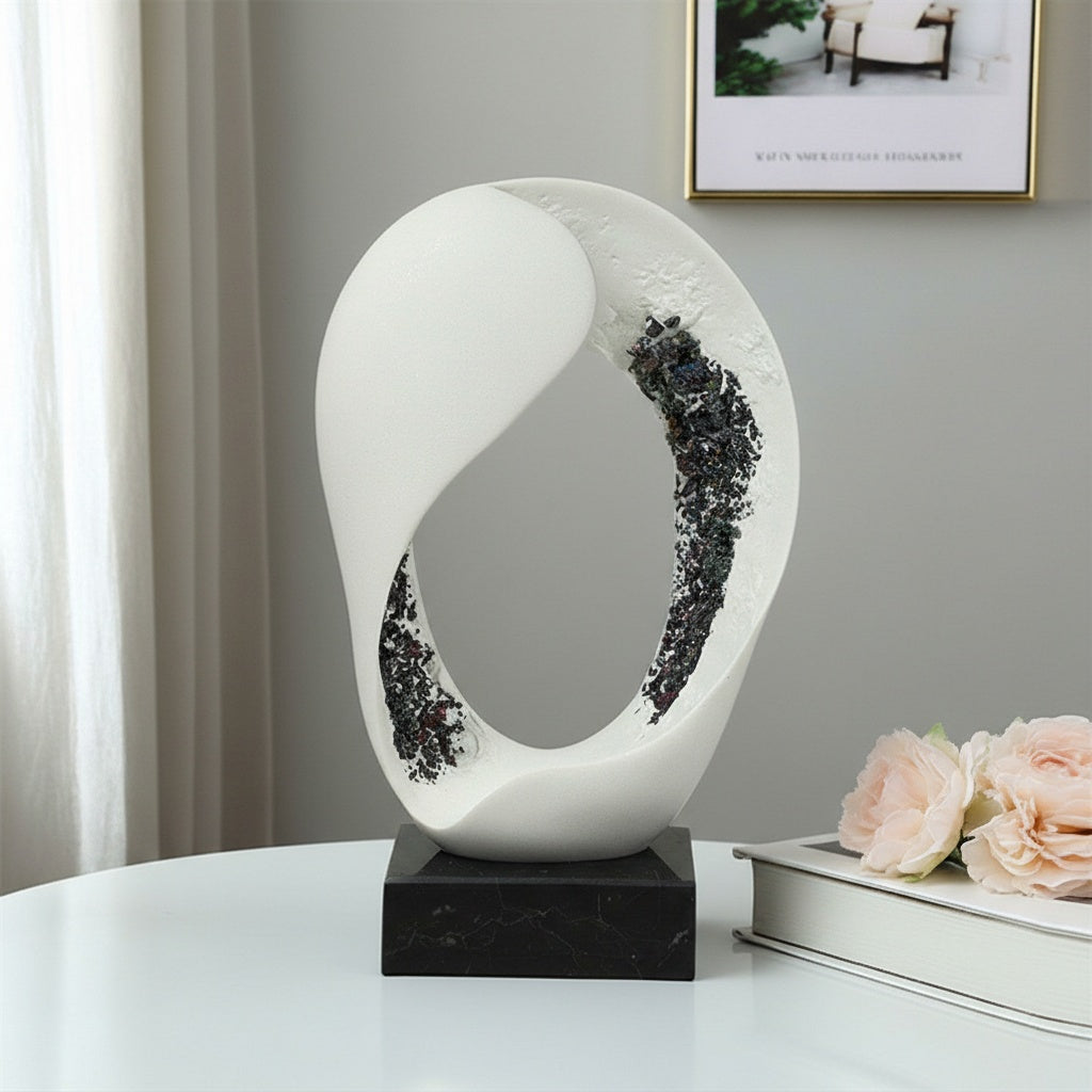 Front view of white abstract sculpture with dark textured inlay on black marble base