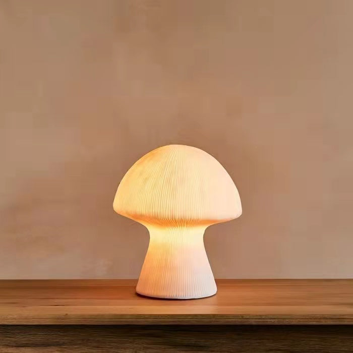 Front view of lit white mushroom lamp on wooden table